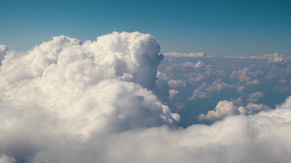 Aerial view from airplane window of white puffy clouds on bright sunny day. alt