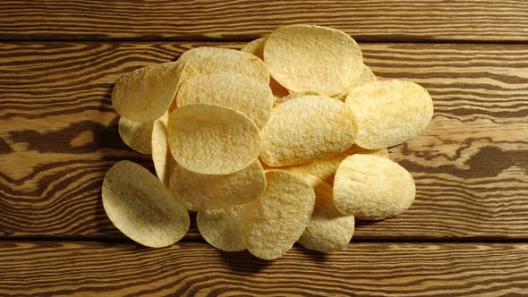Potato chips appear one by one on wooden table