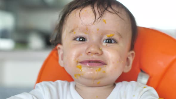 Closeup of the Face of a Beautiful Child Smeared with Food Who Sits on a Chair and Indulges Pulls alt