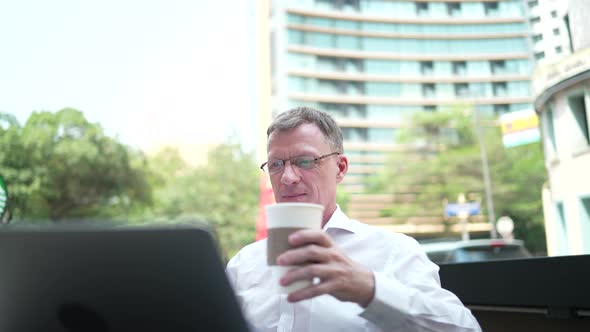 senior businessman working confident on a laptop, business person man working outside office in city alt