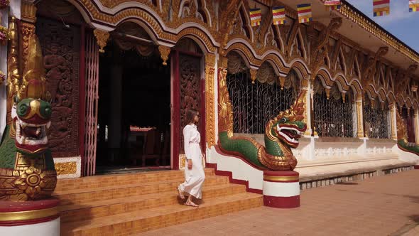 Young woman tourist go down the stairs in Buddhist Wat Luang Temple, dragons. Travel in Pakse, Laos alt