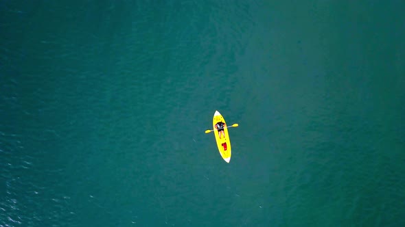 Aerial top down shot of an unrecognizable man rowing against current at the sea alt