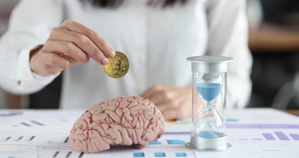 Female Hand Inserts Bitcoin Coin Into Human Brain alt