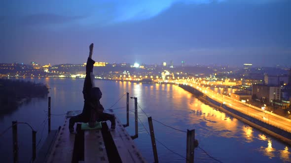 Young Man Practicing Yoga on the Edge of Bridge in the Evening, Doing Headstand alt
