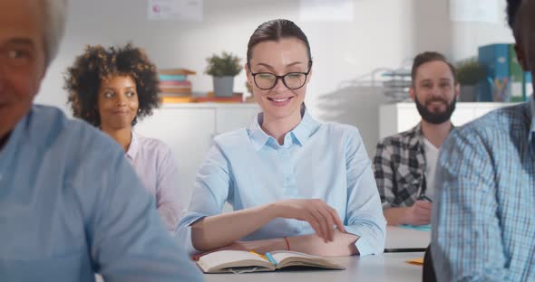 Young Woman in Glasses Attending Education Courses and Raising Hand to Ask Questions alt