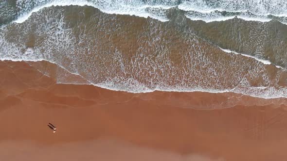 Northern Spain. Flying Over Ocean Sandy Beach. Couple of People Walking the Deserted Beach. Aerial
