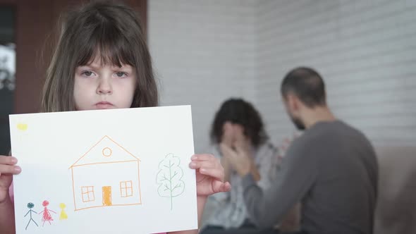 A child with a picture of a happy family. Aggression in the family. Divorce.  alt