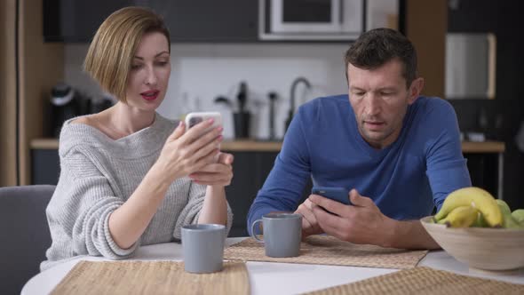 Absorbed Caucasian Adult Couple Surfing Social Media on Smartphones Ignoring Each Other alt