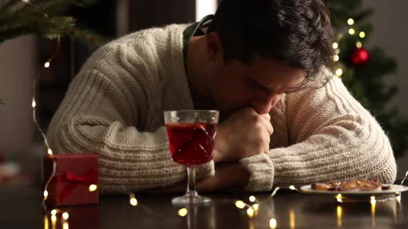 sad man sitting at the holiday table at Christmas