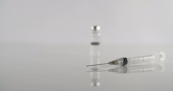 Empty Syringe and Vaccine on a White Surface alt