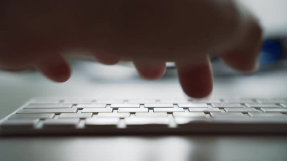 Male hands typing on a white computer keyboard
