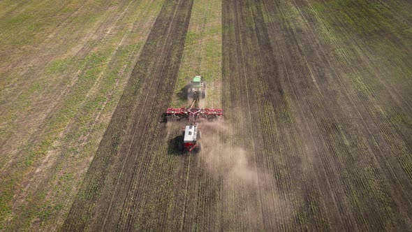 Tractor plowing and fertilizing the agricultural fields in the springtime alt