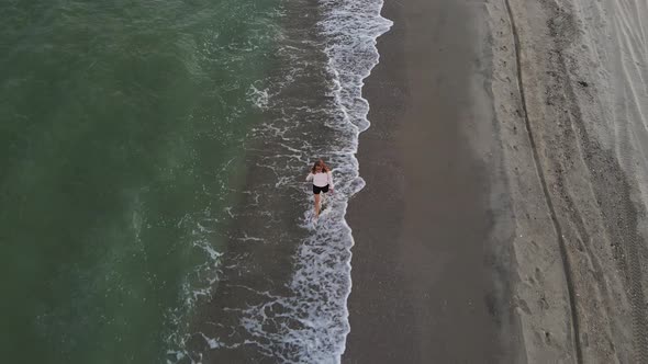 Beautiful Barefoot Woman Walking Along Deserted Beach alt