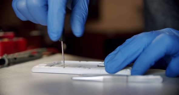 Repairman in Electronics Repair Service Disassembling Smartphone with Screwdriver Fixing Broken alt