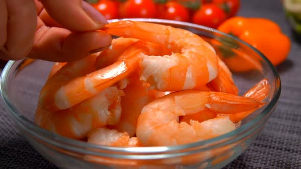 A Female Hand Lays a Delicious Shrimp in a Glass Bowl  alt