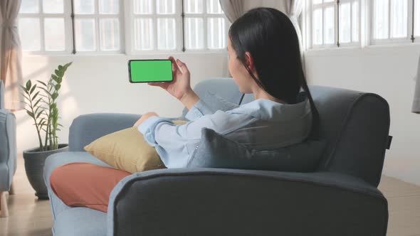 Female Using A Smartphone With Green Screen Display alt