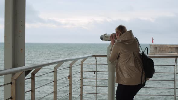 Woman looking at sea through binoculars at view point