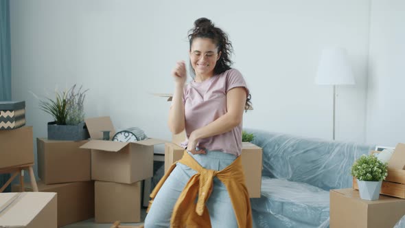 Asian Woman is Dancing in Modern Apartment After Relocation Enjoying Music in Free Time at New Home alt