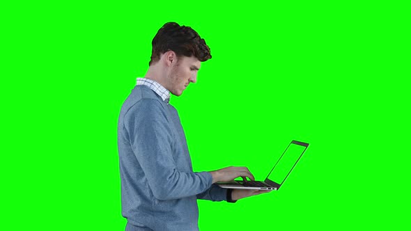 Caucasian man using a laptop on green background