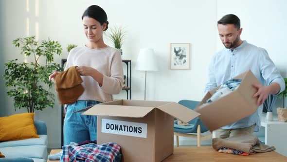 Generous Family Sharing Clothes and Toys Packing Boxes for Donation Doing Charity Indoors at Home alt