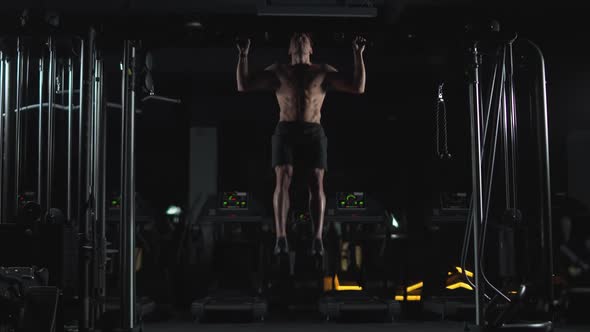 Wellness Athletic Man Performs Pullups on the Horizontal Bar Strength Training in the Gym at Night alt