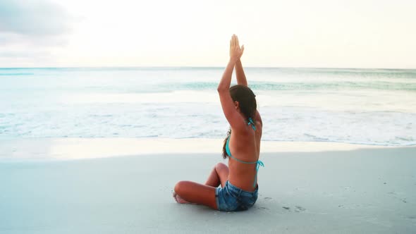 Woman performing yoga on beach alt
