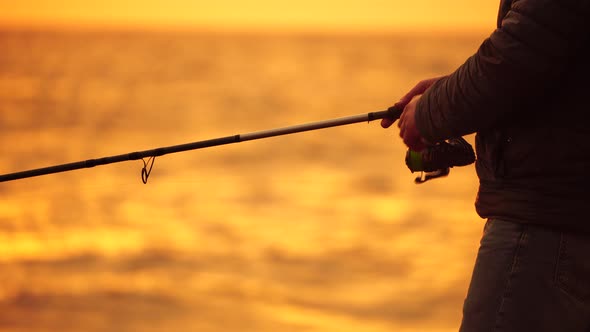 Silhouette of a Man Tightens a Fishing Line Reel of Fish Summer alt