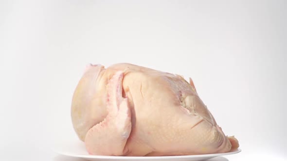 The chicken carcass lies on a platter and rotates on a white background alt