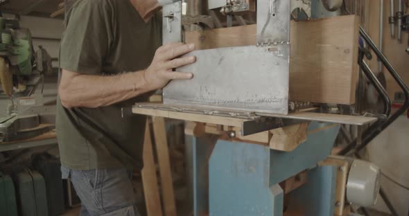 Carpenter with a mask running a saw machine