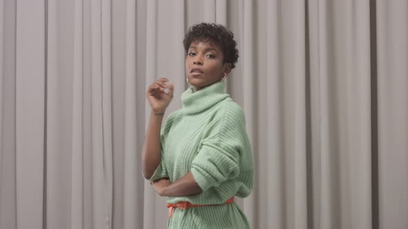Woman in Mint Sweater in Studio with Grey Curtain Background alt