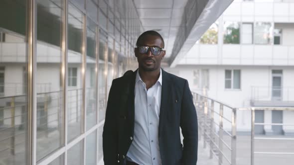 Afroamerican Businessman Walking Next to Office Building Holding Shoulder Bag Outdoors alt