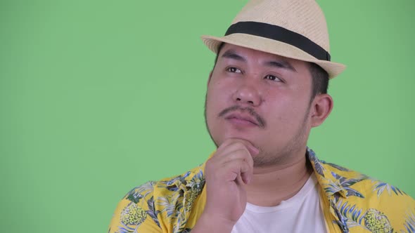 Face of Happy Young Overweight Asian Tourist Man Thinking alt