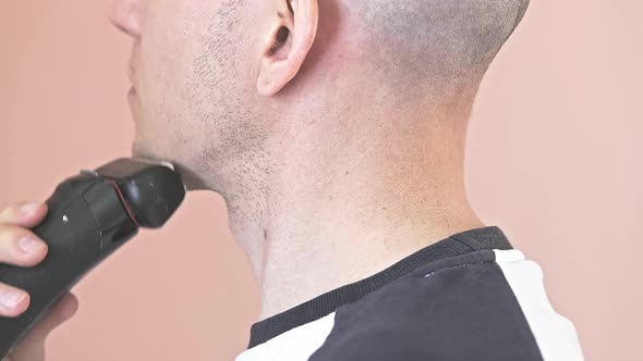 The Bald Young Man Shaves His Neck with an Electric Shaver