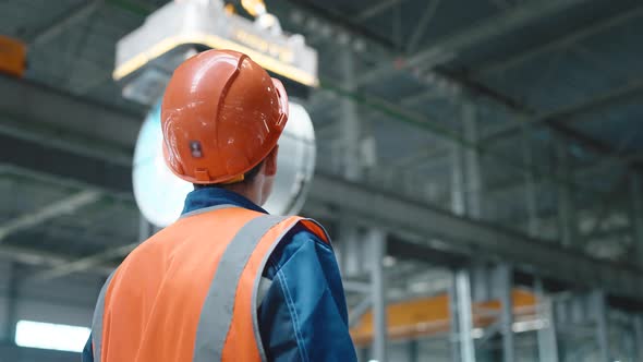 A Working Crane Operator is Engaged in Loading Rolled Metal Products at an Enterprise or Warehouse alt