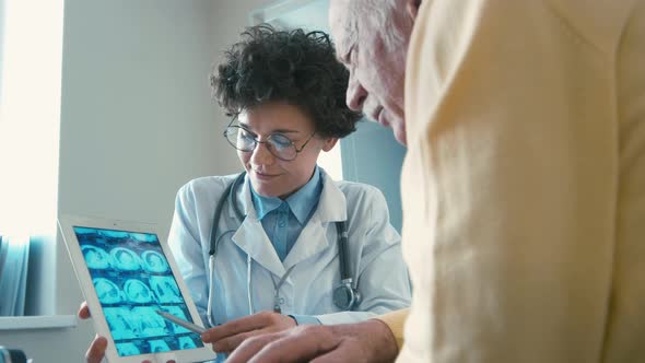 Female doctor showing ultrasonography images to old man