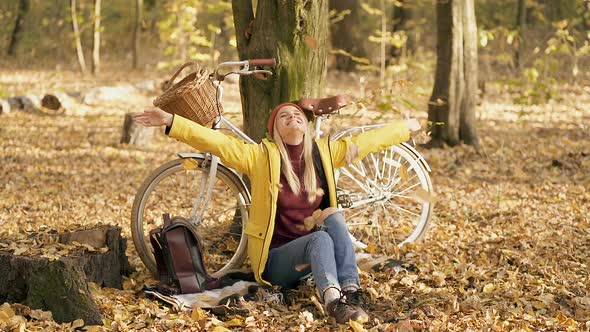 Woman Sitting Near the Tree and Bicycle in The Autumn Forest