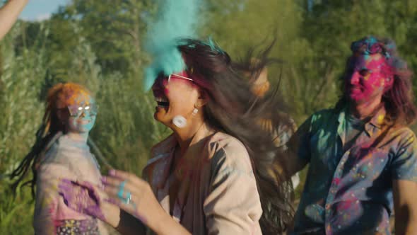 Multiethnic Group of Friends Dancing and Throwing Paint Powder Enjoying Holi Celebration Outdoors alt