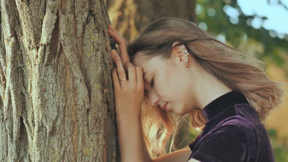 Sad Girl Leans on a Tree in Depression alt
