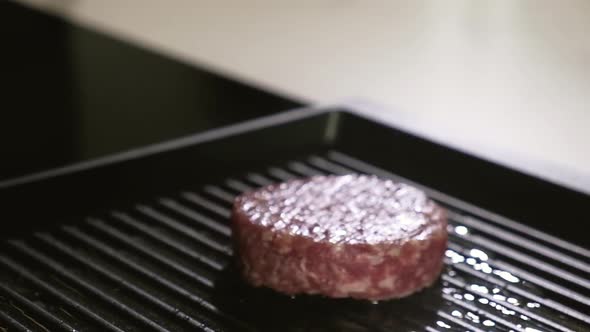 Chef puts raw meat for burger grill pan. Cooking delicious grilled hamburger alt