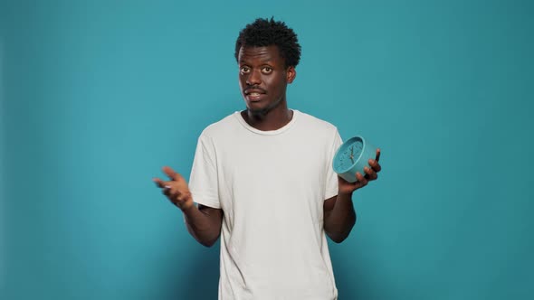 Portrait of Man Holding Wall Clock and Talking to Camera alt