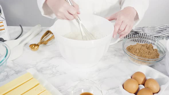Step by step. Mixing ingredients in a glass bowl to make chocolate chip cookies. alt