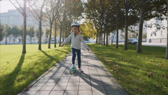 Little Girl is Slowly Skateboarding in Protective Helmet Steadicam Shot