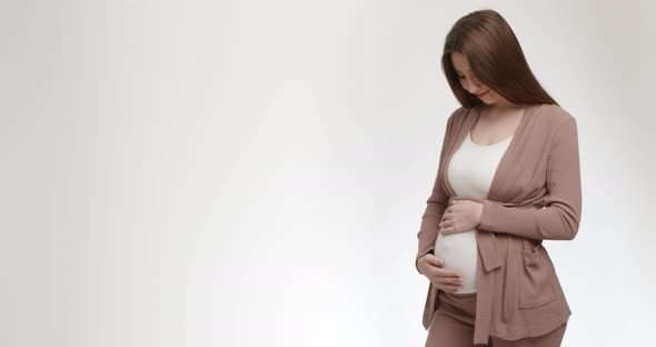 Happy Young Pregnant Woman Stroking Her Big Belly White Studio Background with Empty Space alt