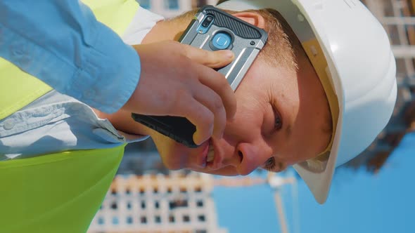 Vertical Screen Civil Engineer Talking on Phone Against Construction Site alt