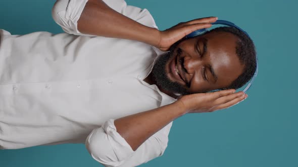 Vertical Video Smiling Adult Using Headphones to Listen to Mp3 Radio Music alt