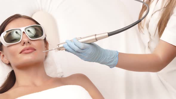 Cosmetologist in Gloves Working on Female Face with Beauty Machine alt
