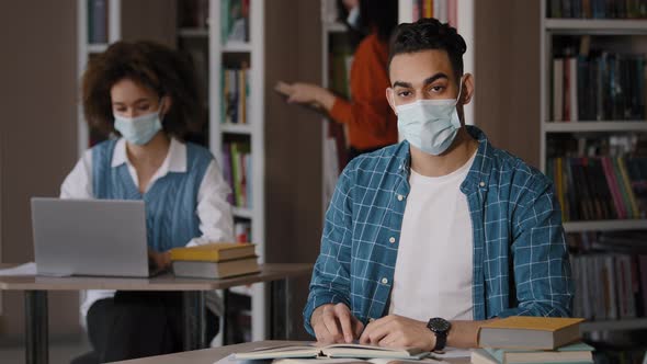 Young Clever Guy Student in Protective Mask Writes Notes Prepares for Exam Makes Project Writing alt
