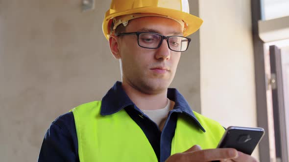 Male Builder in Helmet with Smartphone