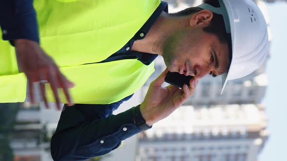 Vertical Screen Building Contractor Talking on Phone Against New City District alt