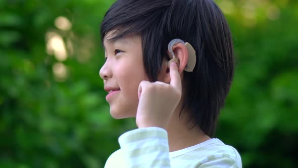 Asian Child With Hearing Aid Behind The Ear Outdoors alt